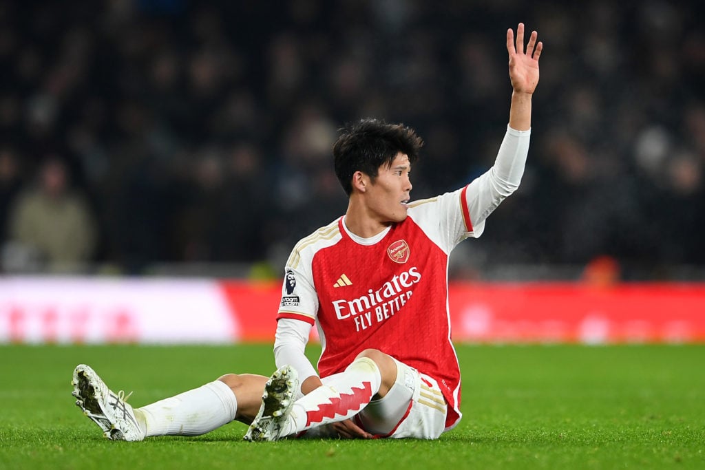 Takehiro Tomiyasu signals to the medical staff after suffering an injury