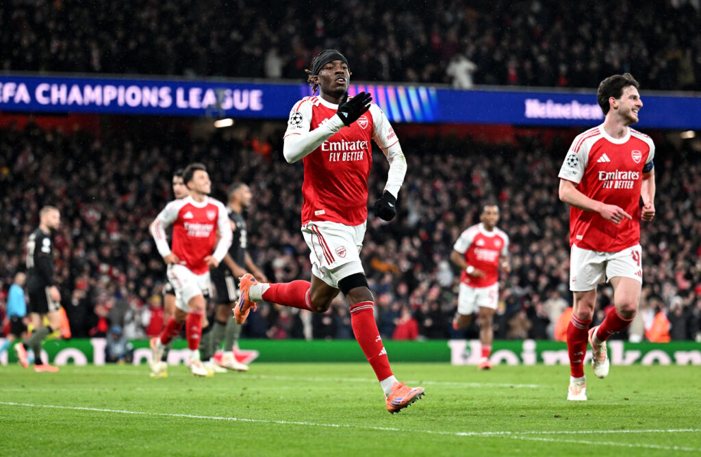 Noni Madueke taps the badge during Arsenal v Bayern Munich in the UEFA Champions League.