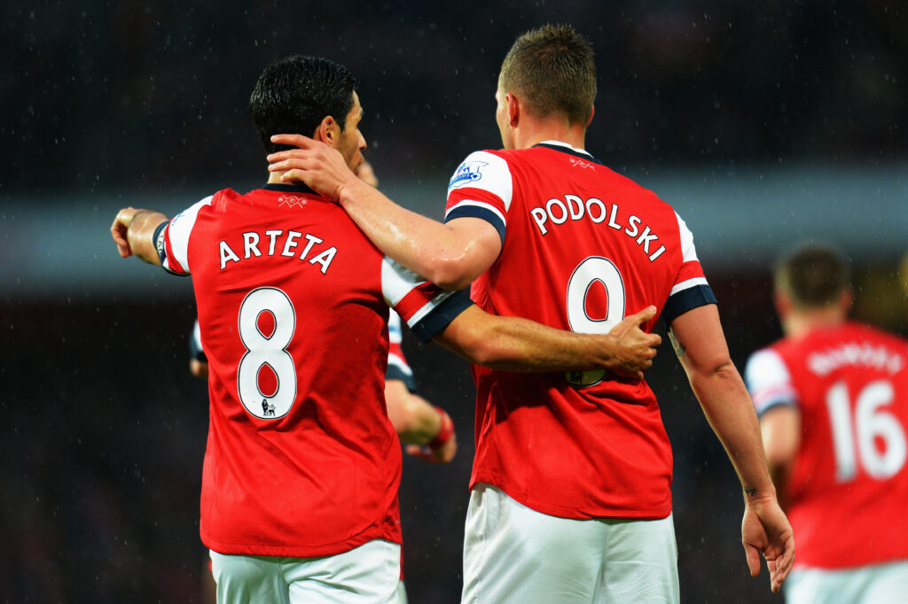 Lukas Podolski of Arsenal celebrates with team mate Mikel Arteta after scoring during the Barclays Premier League match between Arsenal and Wigan Athletic at Emirates Stadium.