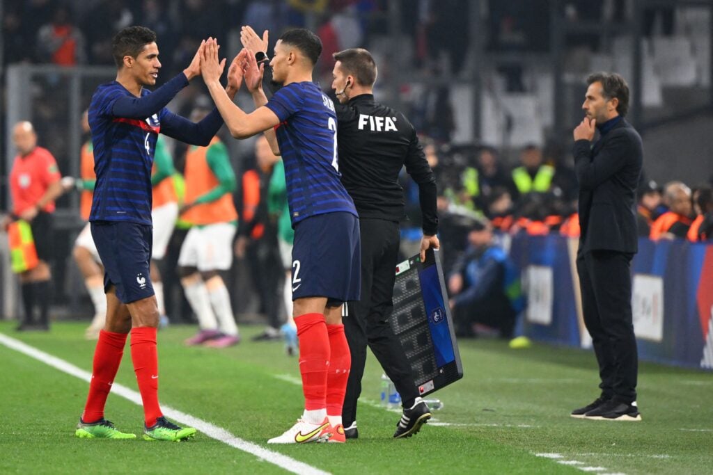 William Saliba shakes hands with Raphael Varane before replacing him during a France game